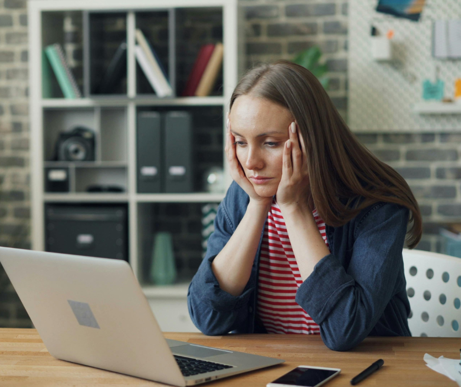 Woman stressed while looking at a charge-off on her credit report on her laptop